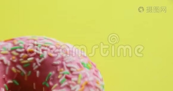 明亮和五颜六色的甜甜圈特写镜头旋转在黄色的背景。 美味的甜面圈在旋转视频