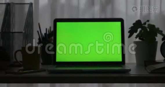 带有绿色屏幕的笔记本电脑。 黑暗的办公室。 多利加入。 完美地放置你自己的图像或视频。 正在使用的技术绿色屏幕。 语文视频