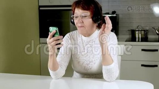 一位老年妇女从电话里用耳机听音乐，积极地做手势，跳舞视频