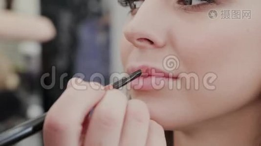 专业化妆师女士为美容院的客户画嘴唇。视频