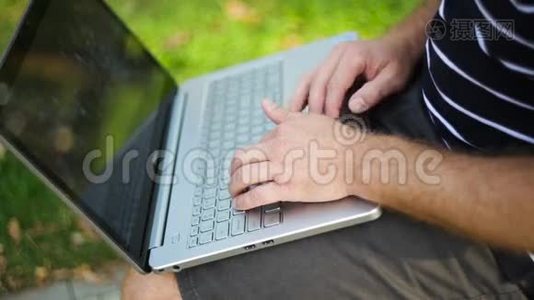 坐在公园长椅上的年轻人，腿上放着笔记本电脑视频