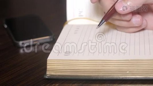 男人用钢笔在笔记本上手写东西，但电话铃响了。闭合视频