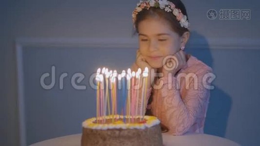 一个小女孩看着节日蛋糕上的蜡烛，慢慢地许愿视频