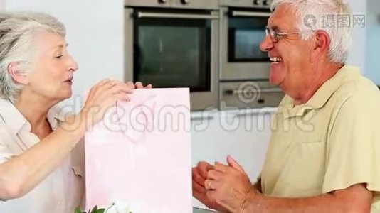一位老人给他的搭档一个粉红色袋子里的礼物视频