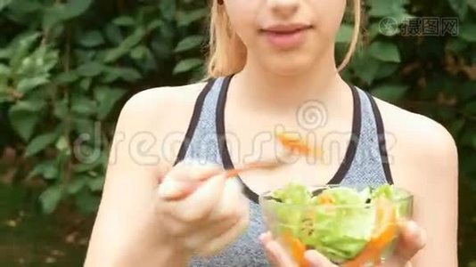 年轻女孩在锻炼后吃蔬菜沙拉。视频