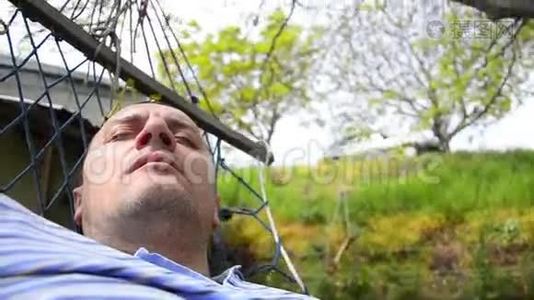 男人睡在吊床上打哈欠视频