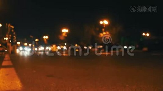 城市的夜间交通。在夜间道路上开有灯的散焦汽车。视频