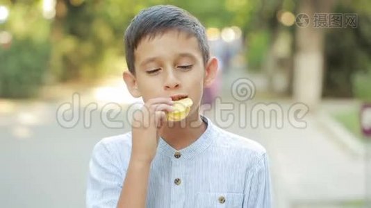 在街上吃薯片的男孩。 小男孩吃垃圾食品视频