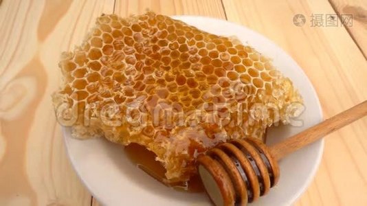 蜂蜜滴在蜂窝上，黄色背景。 慢动作视频