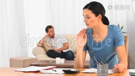 丈夫在沙发上时，美丽的女人看着她的账单视频