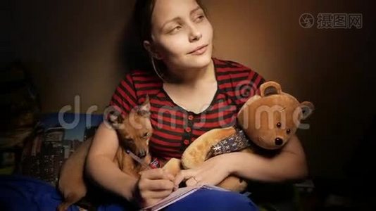 十几岁的孩子在家里写日记，她带着一只玩具熊和一只小狗。 4UHDK视频