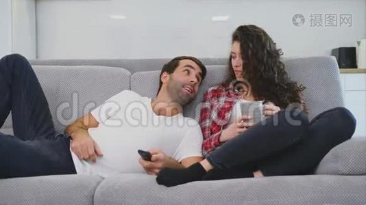 年轻夫妇在他们的公寓里放松，躺在沙发上看电影。视频