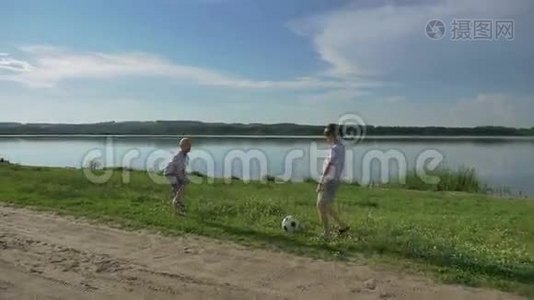 父亲和两个儿子白天在海滩上踢足球。友好家庭的概念。视频