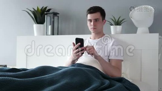 男人躺在床上用智能手机视频