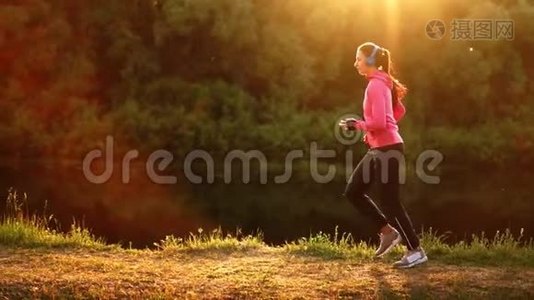 清晨在阳光明媚的黎明时分，在池塘附近的公园里慢跑，女孩正准备去马里亚诺，带领一个健康的人视频