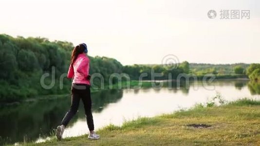 清晨在阳光明媚的黎明时分，在池塘附近的公园里慢跑，女孩正准备去马里亚诺，带领一个健康的人视频