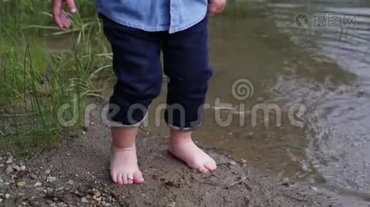 小男孩沿着河走。 那孩子在湖边跑。 慢动作。 快乐的婴儿在水边玩耍。 宝贝视频