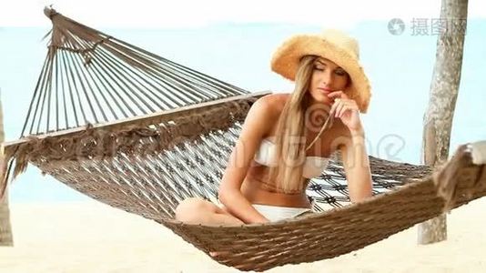 在海滩上坐在吊床上的漂亮女人视频