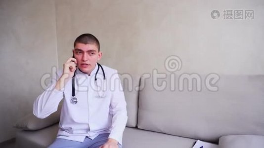 手机医生给坐在医院办公室沙发上的病人提供建议。视频