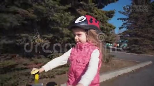 五岁的金发小女孩在一个旧公园骑自行车。视频