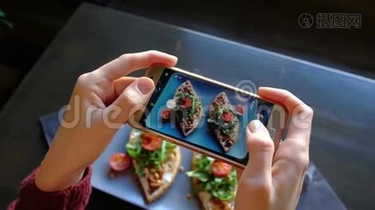 女手在餐厅用智能手机拍摄开胃的食物。视频