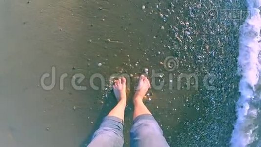 女孩站在海边，海浪拍打着她的脚视频