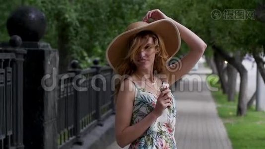 戴着帽子的漂亮年轻女人带着冰淇淋在城市里走来走去视频
