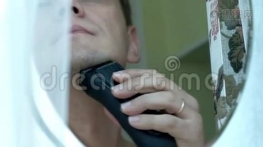 男人用电动剃须刀刮胡子。 检查剃须刀在脸颊上滑动手指。 特写镜头。视频