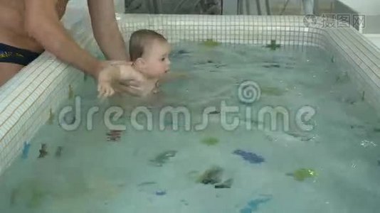 可爱的小孩和爸爸一起在游泳池里的水里游泳视频