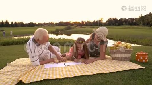 祖父母和孙女在户外画画。视频
