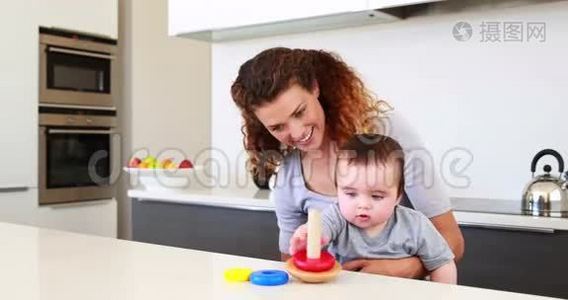 快乐的妈妈和小男孩坐在一起玩木玩具视频