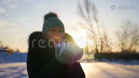 女孩用双手吹雪日落背景视频