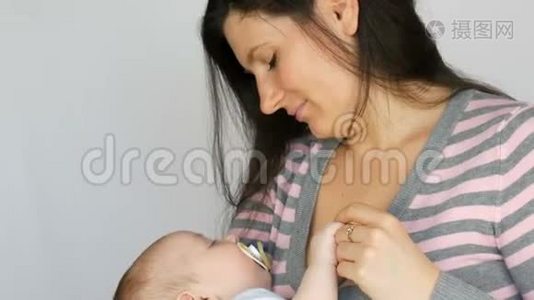 年轻漂亮的、留着一头深色长发的母亲在工作室里怀着一个两个月的新生婴儿视频