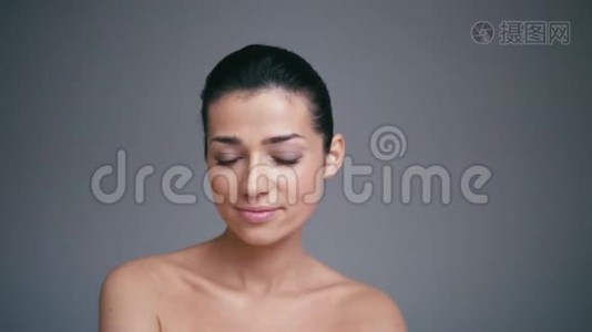 健康女性面部的美容肖像，天然皮肤隔离在灰色背景上。 宇宙学概念视频