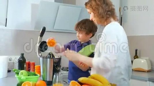 年轻的白种人母亲和孩子在厨房用电榨汁机制作鲜橙果汁视频