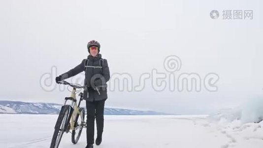人在冰窟附近的自行车旁散步。 有冰洞和冰柱的岩石非常美丽。 骑自行车的是视频