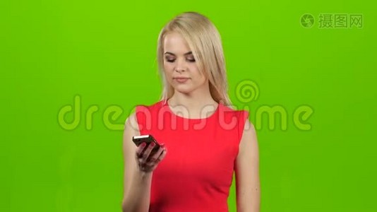 女孩微笑着在绿色屏幕上的手机上交谈视频
