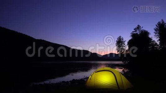 黄色帐篷在山湖畔花费.. 晚安。 在帐篷里，光线燃烧。视频