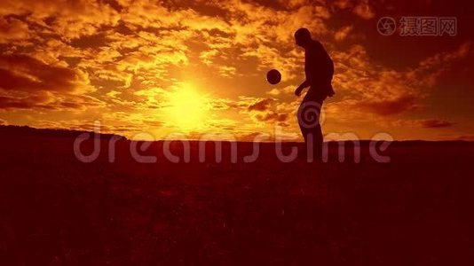 足球运动员填充球剪影人踢球在空中日落生活方式背景。 男人踢足球视频