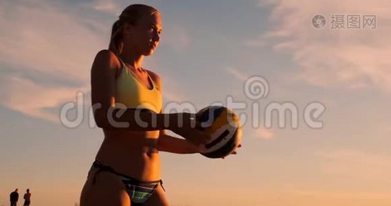 在一个美丽的夏日傍晚，运动女孩在沙滩排球比赛中跳到空中，在网上击球视频