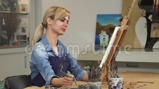 漂亮的年轻女艺术家在艺术工作室创作她的画视频