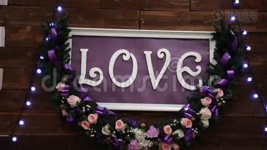 爱的铭文在一个木制的背景，闪烁的灯和花。 装饰艺术动画致力于视频