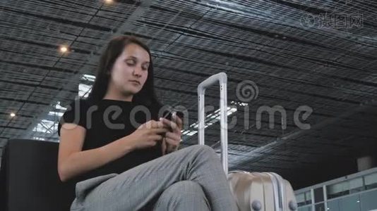 年轻漂亮的女商人在机场使用智能手机，等待排队登记，旅行概念视频
