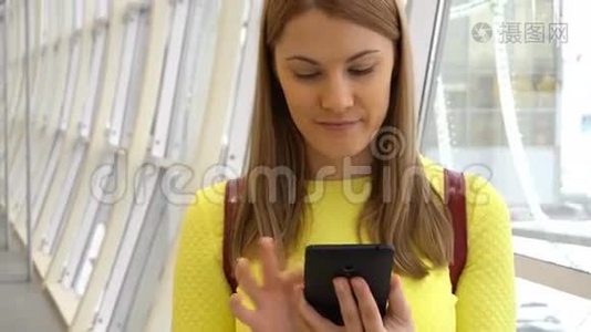 年轻漂亮的女人在商场里带着智能手机。 浏览互联网，与朋友交流。视频
