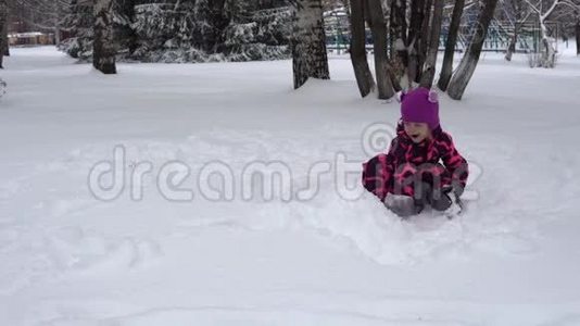 一个穿着粉红色冬季连衣裙的小女孩玩雪。视频