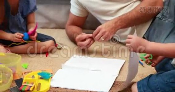 快乐的兄弟姐妹和父母一起在地毯上做工艺品视频
