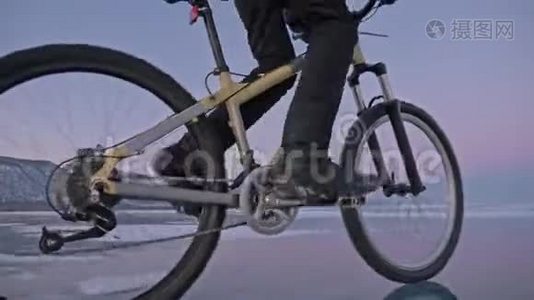 人在冰上骑自行车。 骑自行车的人穿着灰色的羽绒服，背包和头盔。 冰冻的冰视频
