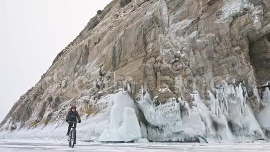 人正骑自行车在冰窟附近。 有冰洞和冰柱的岩石非常美丽。 骑自行车的人穿着视频