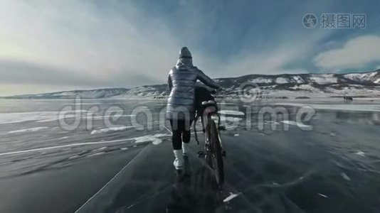 女人在冰上骑着自行车走着。 女孩穿着银色的羽绒服，背包和头盔。 冰冰视频