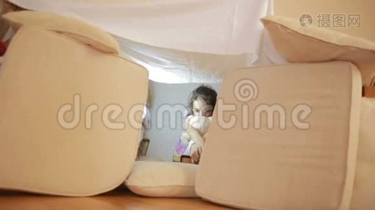 一个小女孩坐在一个临时的枕头屋和一个毯子屋里视频